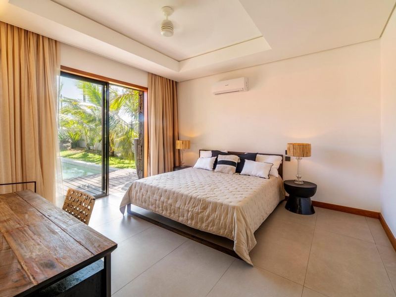 Spacious bedroom featuring a tray ceiling, split-system air conditioning, and large sliding glass doors providing direct access to the outdoor pool area.