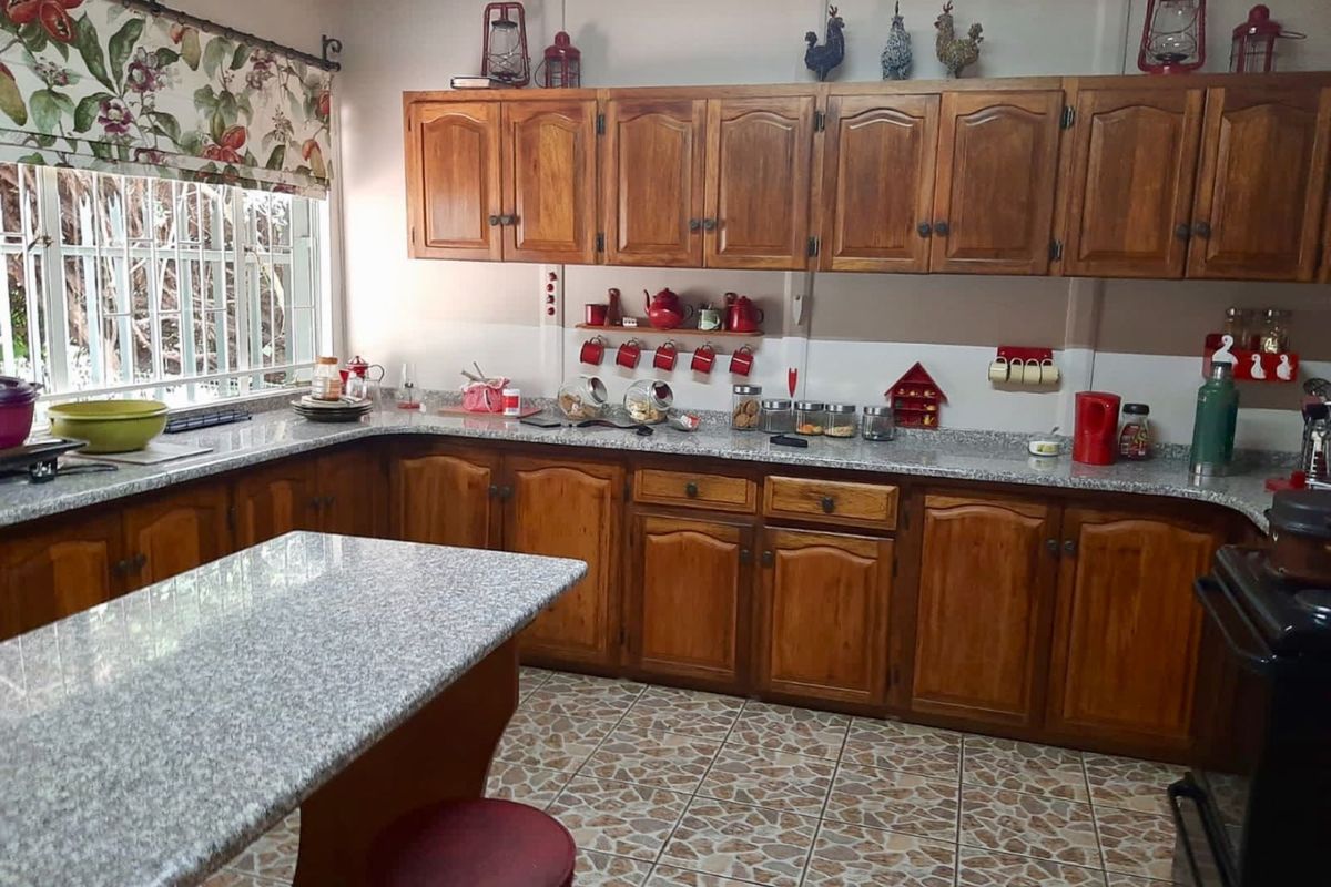A traditional kitchen featuring wooden cabinetry, granite countertops, and tiled flooring, offering a functional workspace with ample storage and a breakfast bar area.