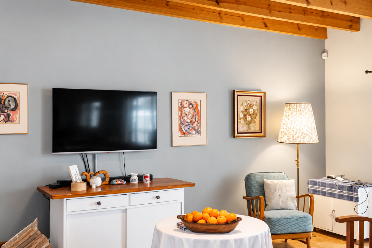 A cozy living room area featuring exposed timber ceiling beams and a wall-mounted television setup.