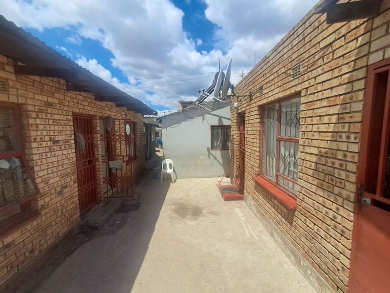 A narrow exterior courtyard area between two face brick structures, featuring concrete paving and security-gated access points.