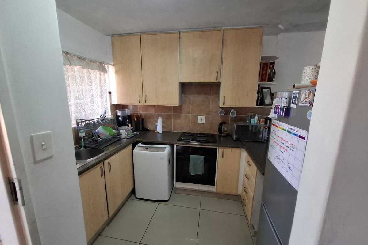 Compact kitchen featuring laminate cabinetry, built-in oven, electric hob, and tiled backsplash, offering a functional layout with potential for modern updates.