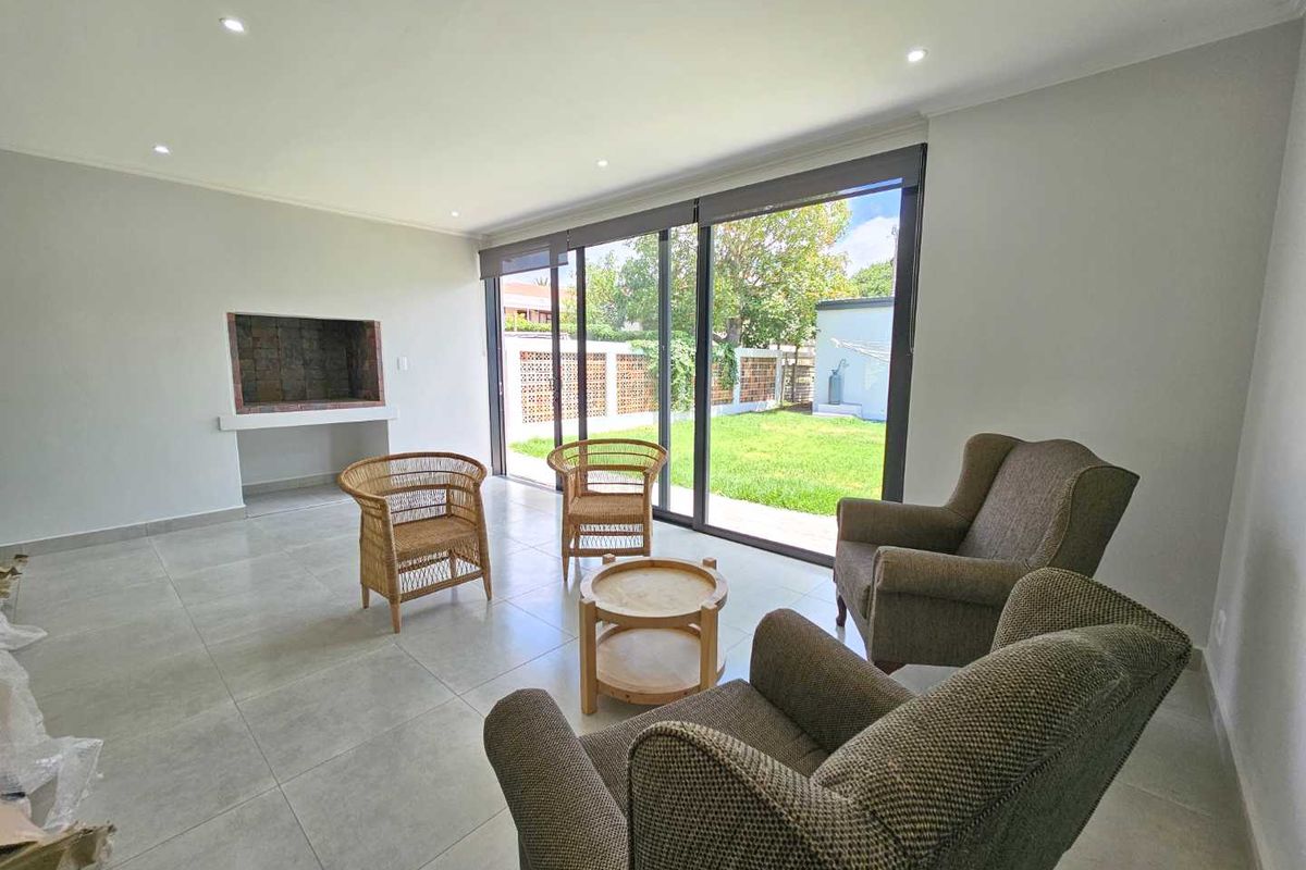 Bright living room featuring large sliding glass doors opening to the garden, recessed ceiling lighting, and a built-in indoor fireplace.