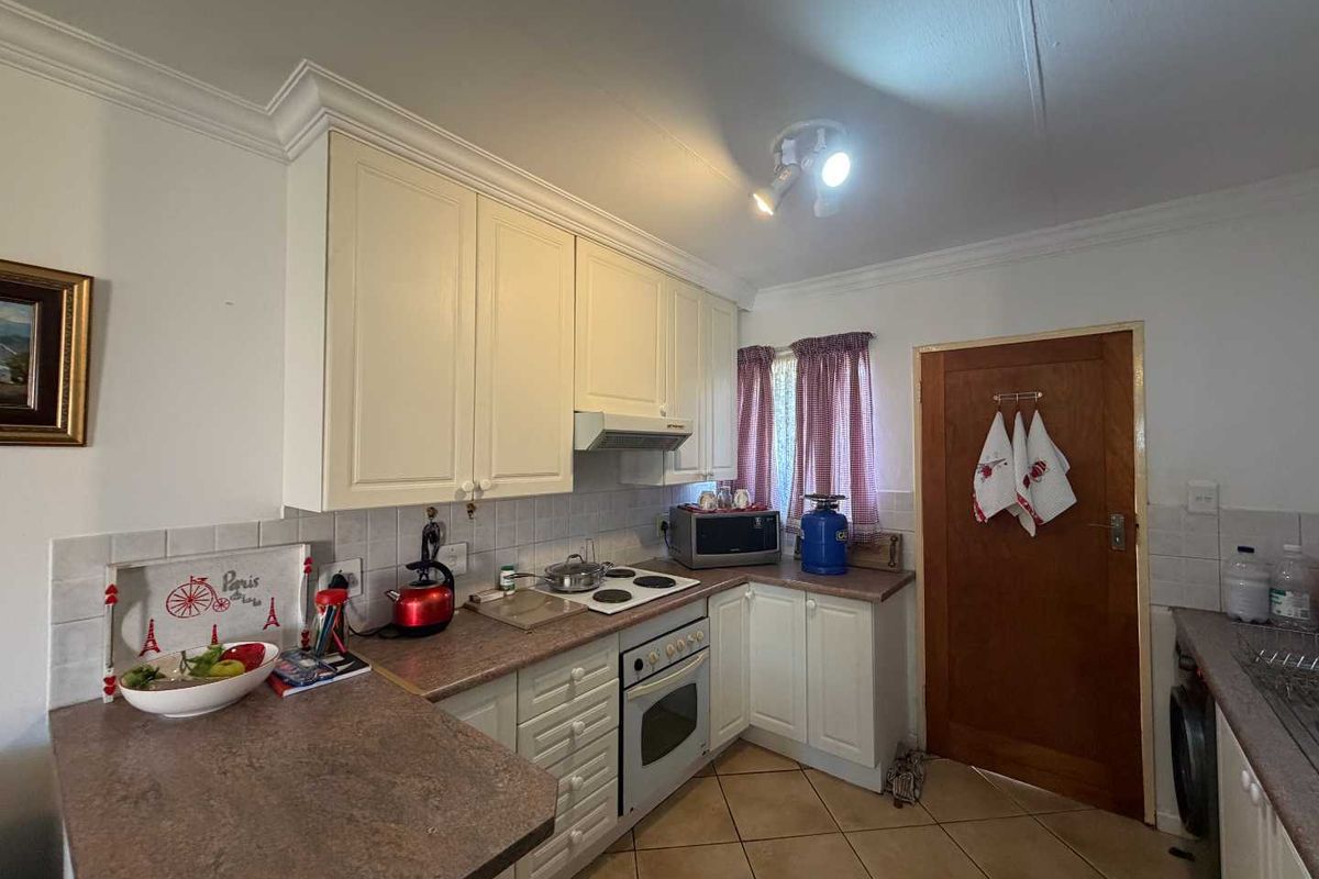 A functional kitchen featuring white cabinetry, laminate countertops, a built-in oven, and a hob with an extractor fan.