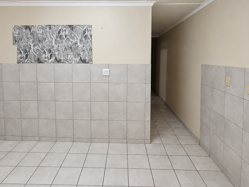 A tiled hallway area featuring neutral wall tiles and electrical points, currently vacant and awaiting finishing touches.