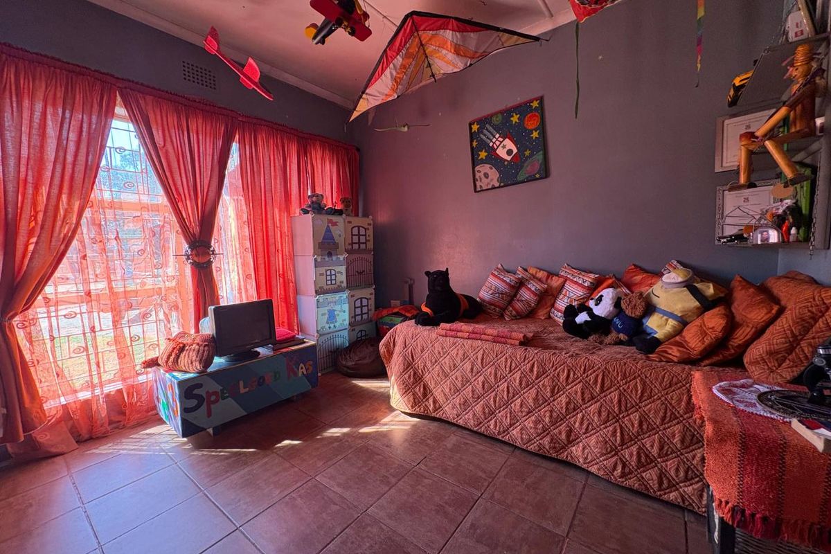 A bedroom featuring tiled flooring, large windows with security bars, and dark-toned walls, providing a functional space with natural light.
