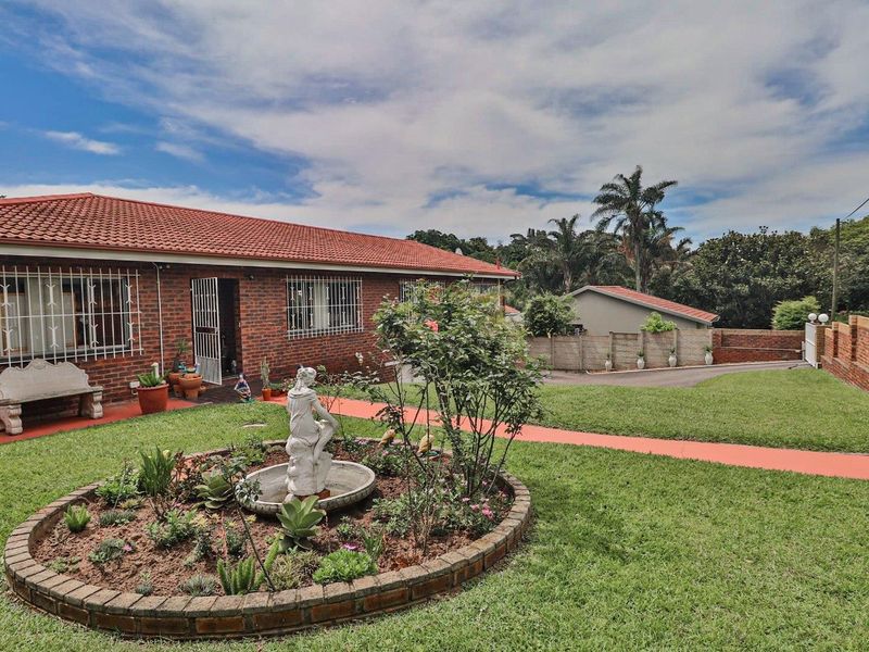 A well-maintained single-story brick house featuring a tiled roof, security bars on windows, and a landscaped front garden with a paved driveway.