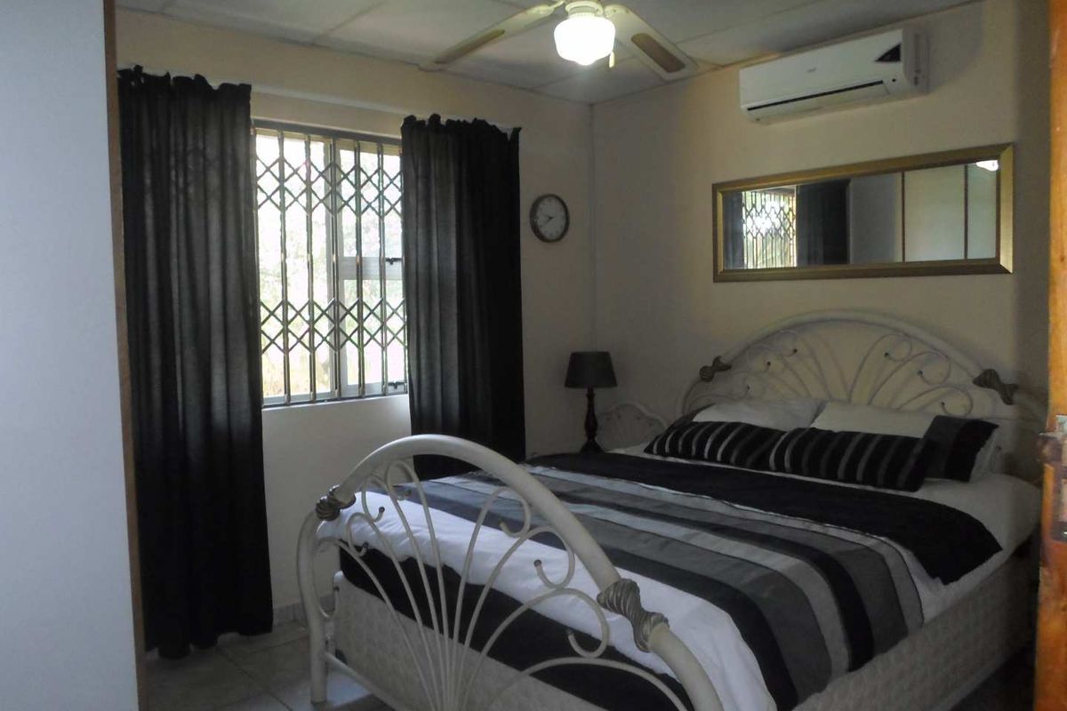 A functional bedroom featuring a ceiling fan, split-system air conditioning, and security bars on the window.