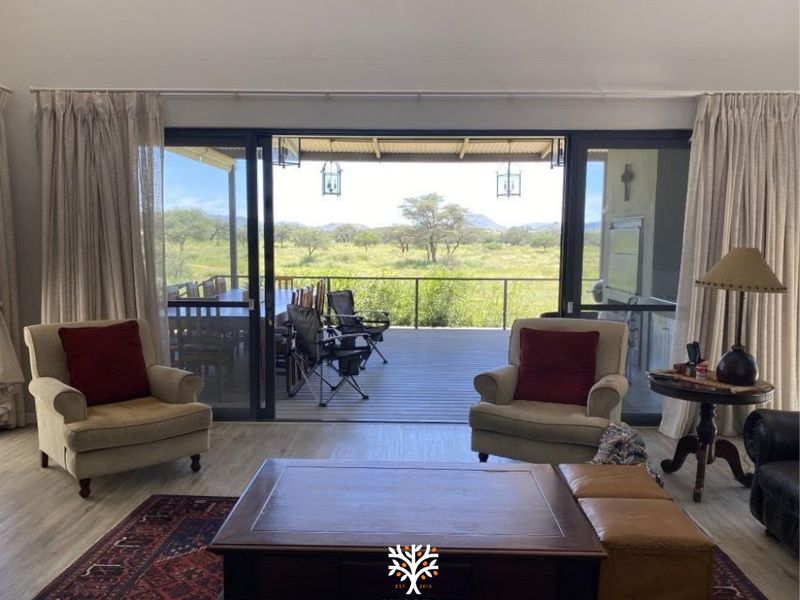 Spacious living room with vaulted ceilings and large sliding glass doors opening onto a covered patio with scenic bushveld views.