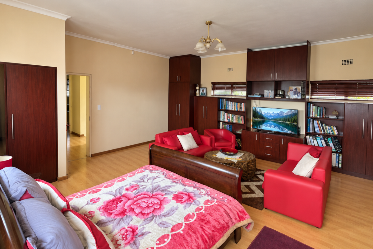 Spacious bedroom featuring extensive built-in cabinetry, integrated shelving units, and light-toned laminate flooring.