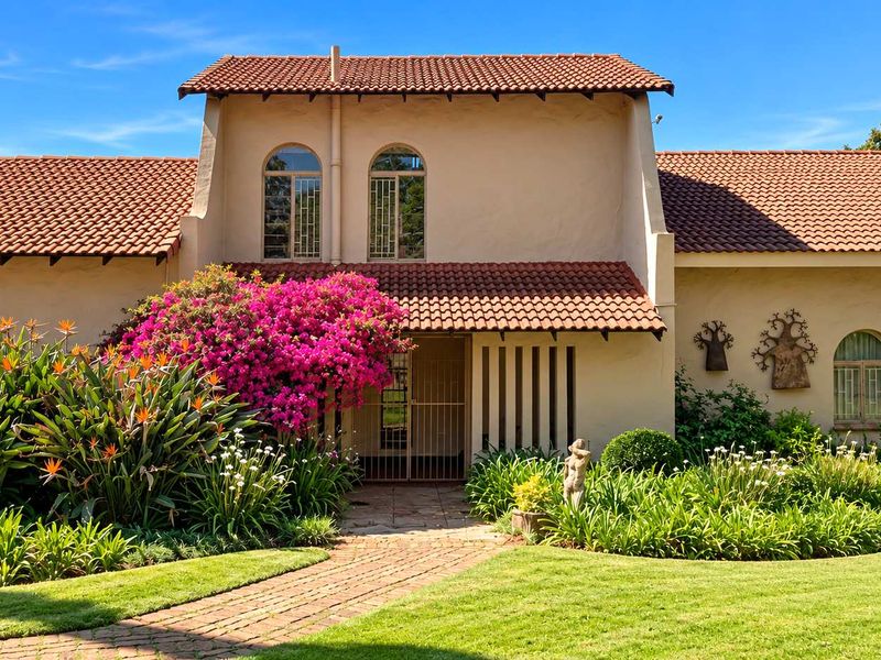 A well-maintained front facade featuring terracotta roof tiles, arched windows, and a charming brick-paved entrance path surrounded by a lush, established garden.