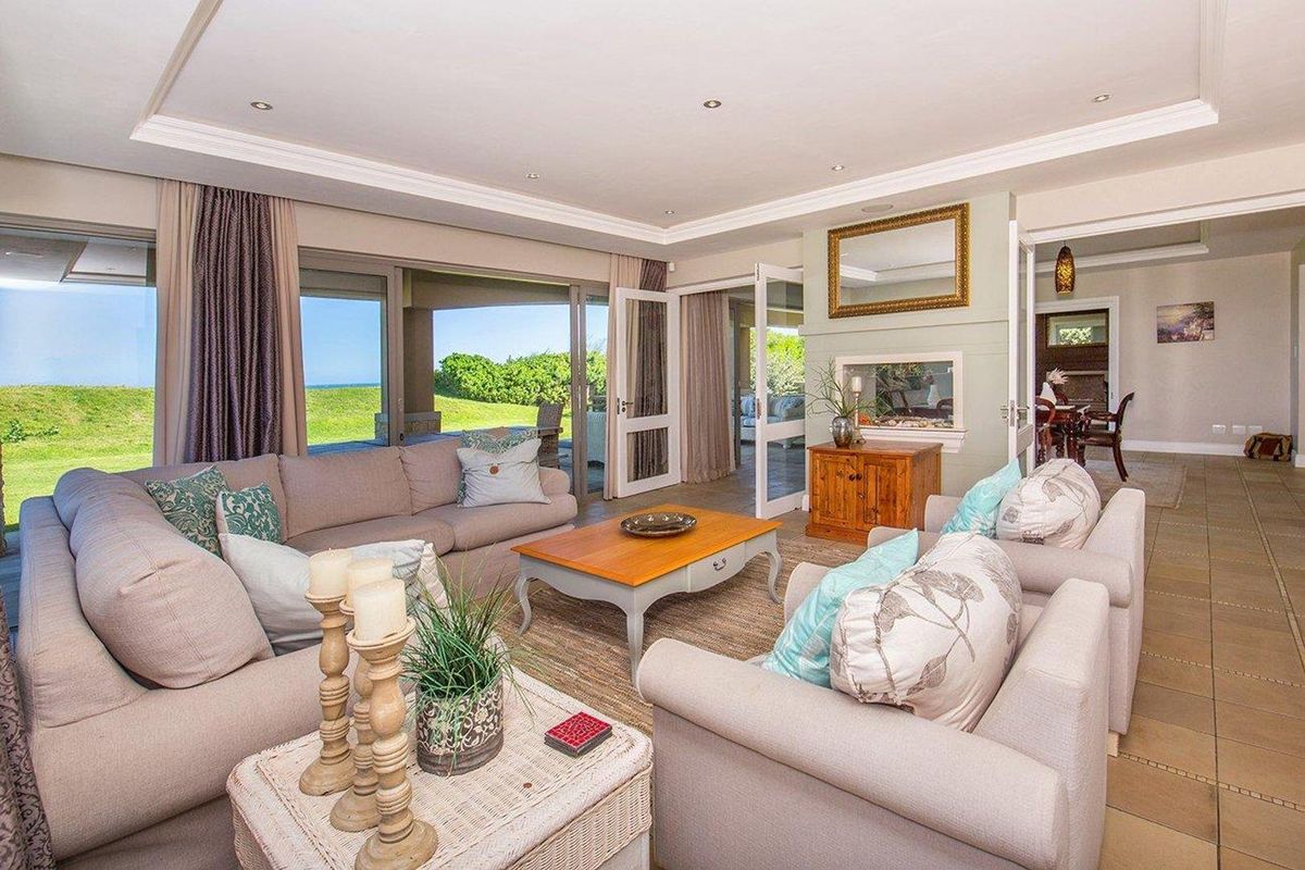 Spacious living room featuring recessed ceiling lighting, tiled flooring, and large glass sliding doors opening onto a covered patio with scenic views.