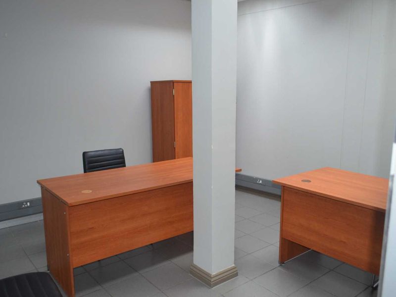 A functional office space featuring tiled flooring, a central structural column, and integrated electrical trunking along the base of the walls.