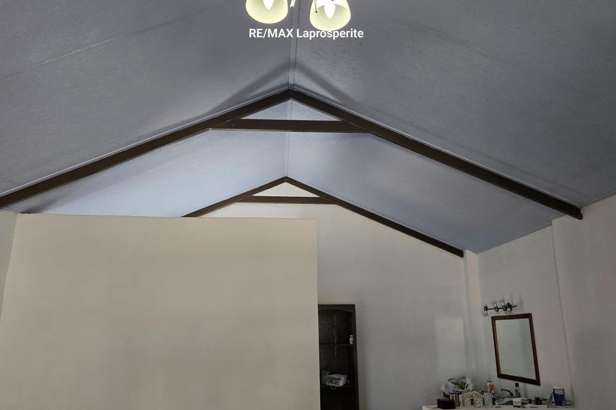 Spacious bedroom featuring a high vaulted ceiling with exposed timber trusses and a built-in vanity area.