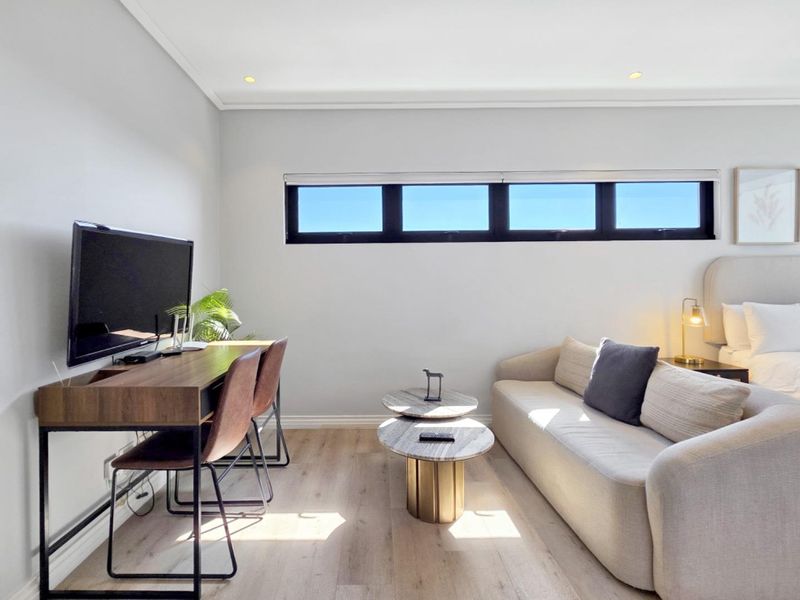 A well-maintained bedroom featuring modern laminate flooring, recessed downlighting, and a horizontal clerestory window providing natural light.