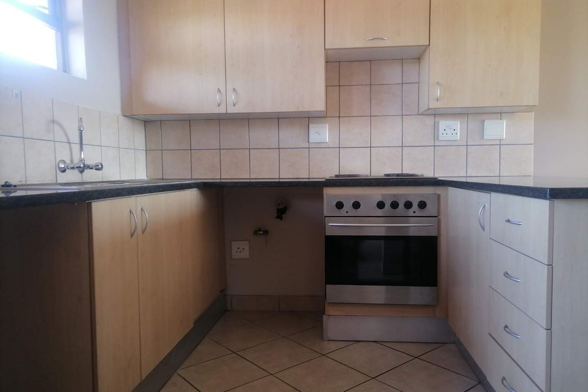 Functional kitchen featuring light wood-finish cabinetry, dark granite countertops, tiled backsplash, and a built-in oven with hob.