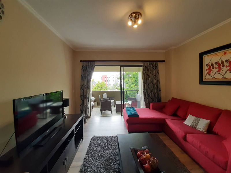 A comfortable living room featuring tiled flooring and a large sliding glass door that provides direct access to an outdoor balcony area.