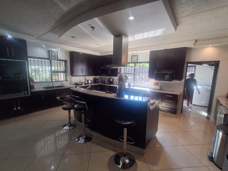 Spacious kitchen featuring dark wood cabinetry, granite countertops, a central island with breakfast bar, and integrated stainless steel appliances.