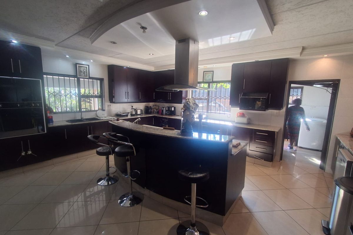 Spacious kitchen featuring dark wood cabinetry, granite countertops, a central island with breakfast bar, and integrated stainless steel appliances.