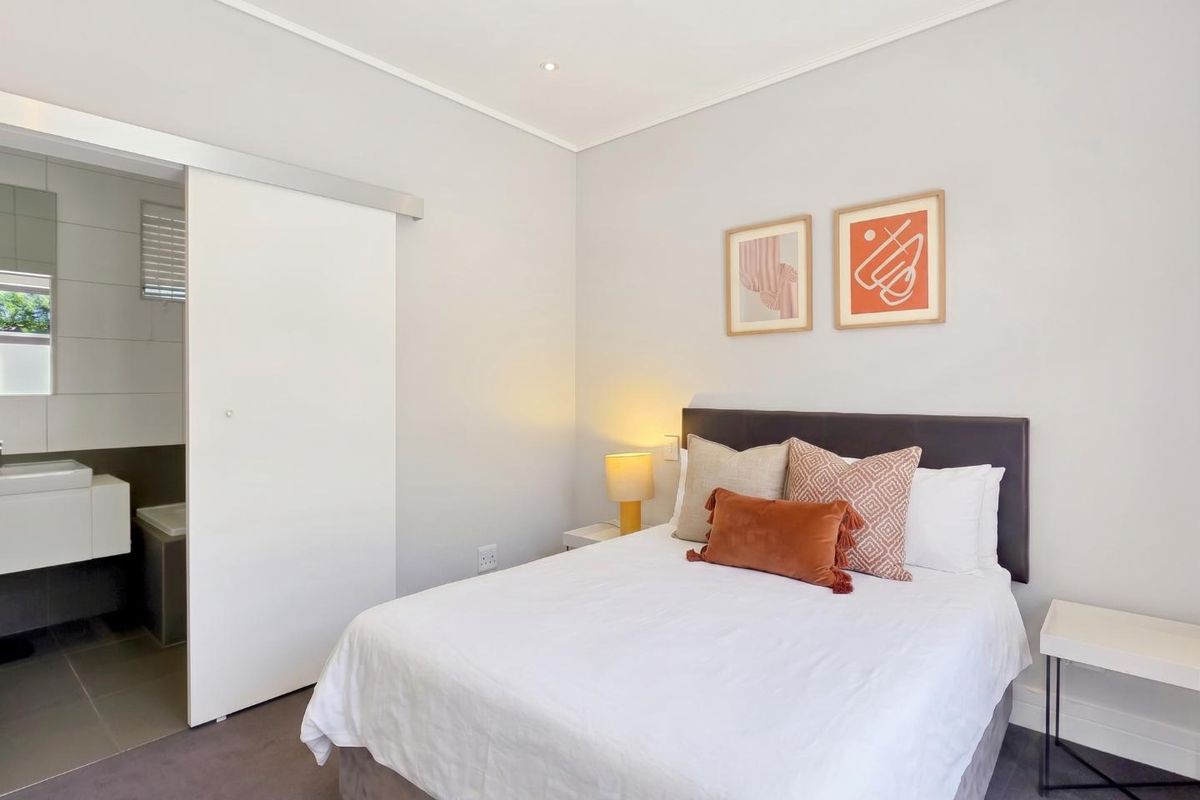 A well-maintained bedroom featuring neutral walls, carpet flooring, recessed lighting, and a sliding door providing direct access to an en-suite bathroom.