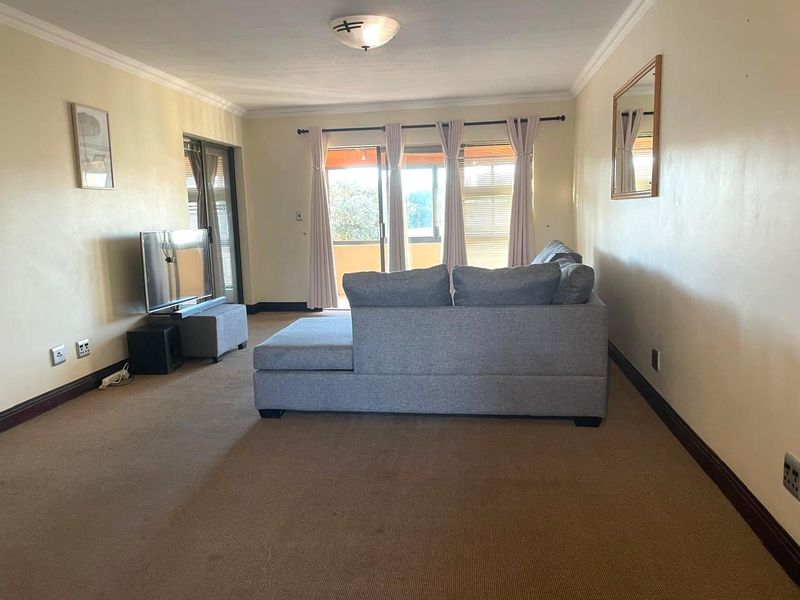 A living room featuring carpeted flooring, neutral walls, and sliding glass doors that provide access to an outdoor area.