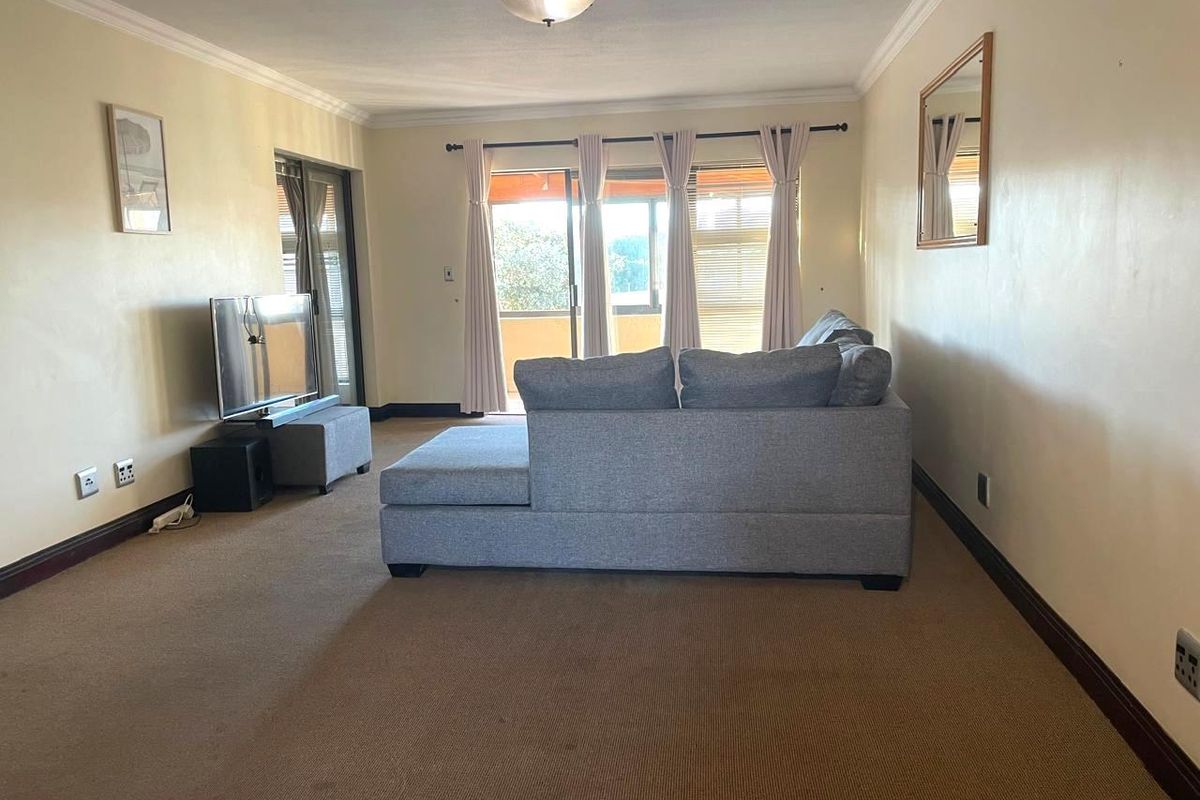 A living room featuring carpeted flooring, neutral walls, and sliding glass doors that provide access to an outdoor area.