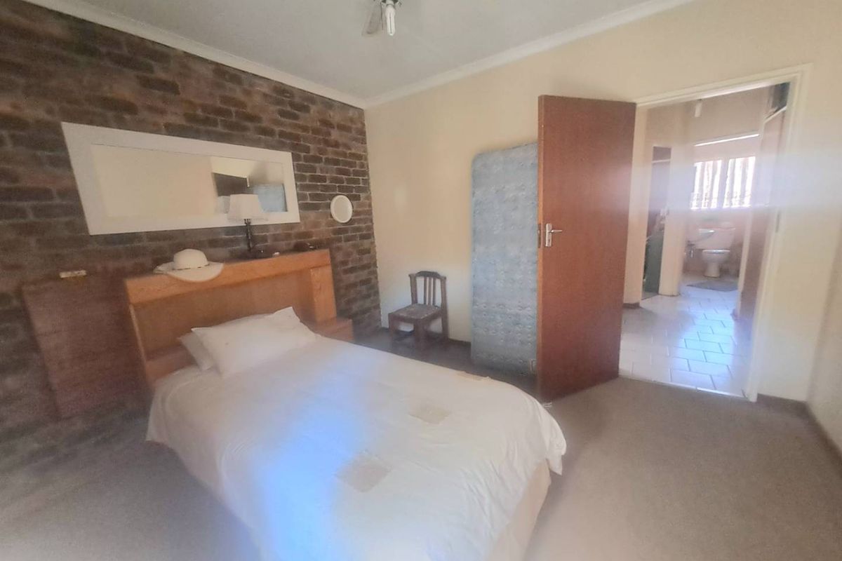 Bedroom featuring an exposed brick wall, ceiling fan, and direct access to an en-suite bathroom.