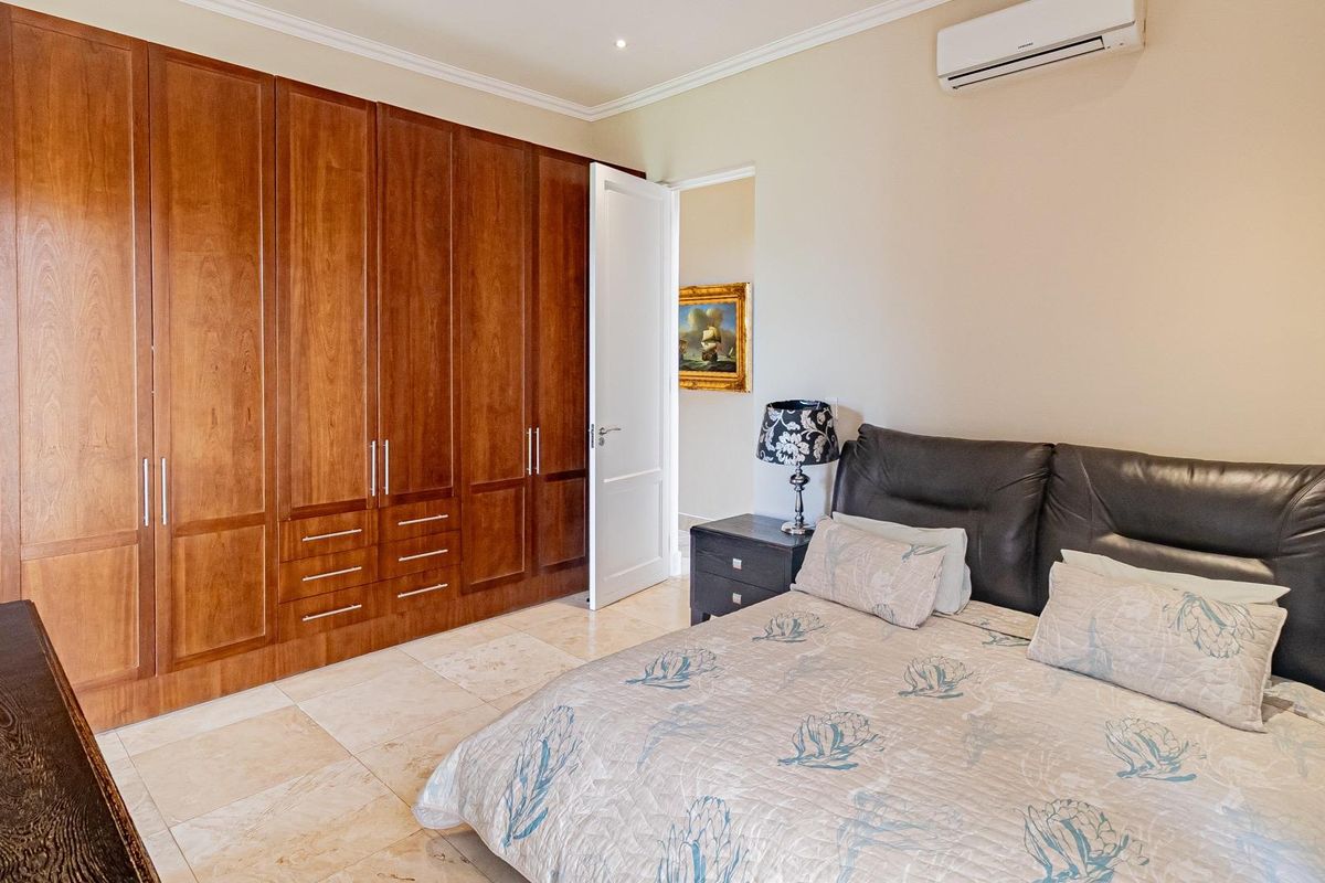 Spacious bedroom featuring extensive built-in wooden cabinetry, tiled flooring, and a wall-mounted air conditioning unit.