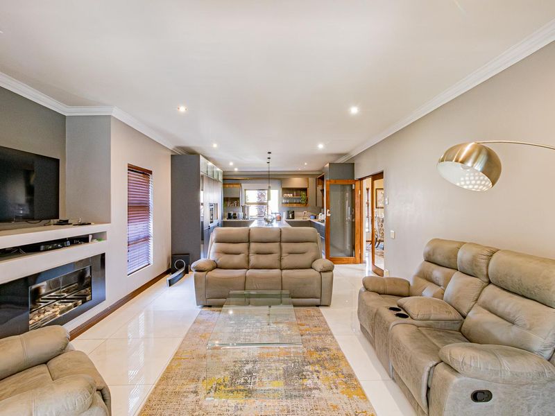 Spacious open-plan living area featuring a modern built-in fireplace, sleek tiled flooring, and a seamless transition into the contemporary kitchen space.