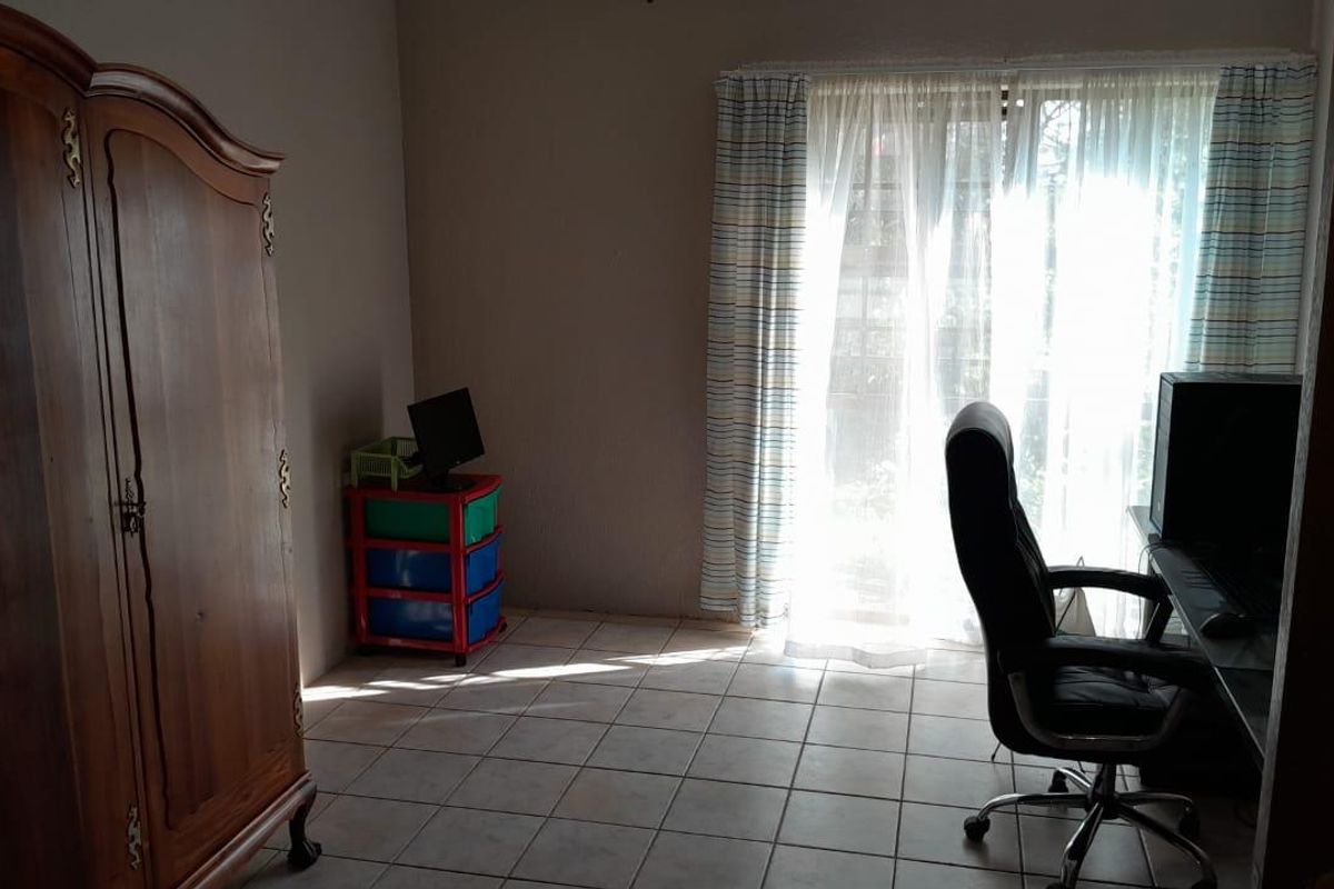 A bedroom featuring tiled flooring and a sliding glass door that provides natural light.