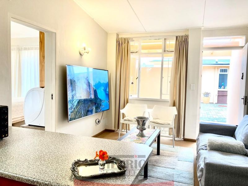 Open-plan living area featuring a granite breakfast bar, neutral wall finishes, and direct access to an outdoor patio space.