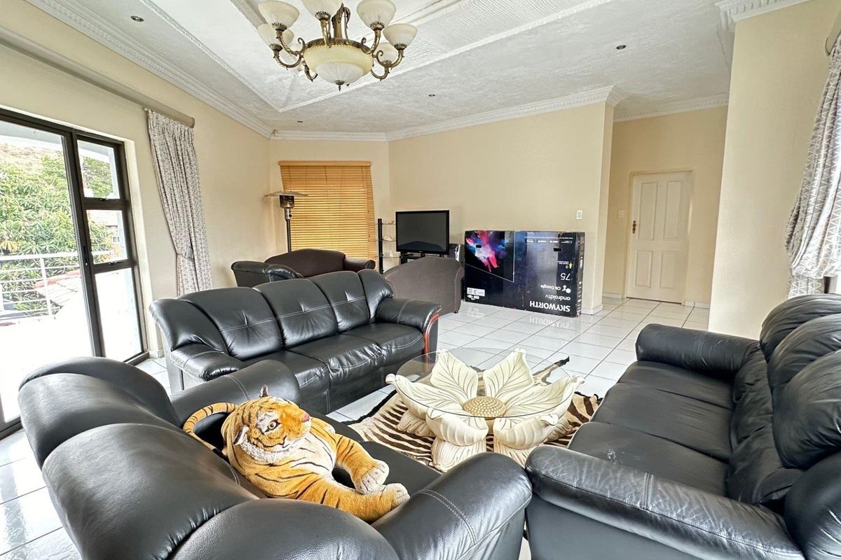 Spacious living room featuring tiled flooring, decorative ceiling cornices, and large sliding doors providing access to the outdoor area.