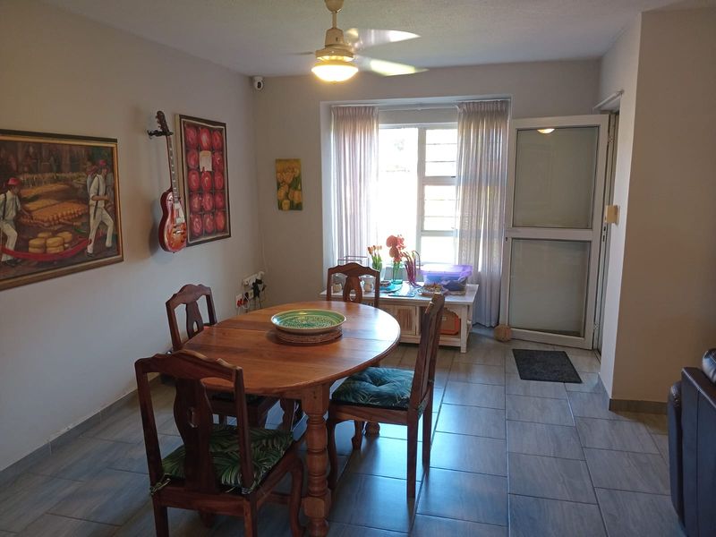 Dining area featuring tiled flooring, a ceiling fan, and natural light through an aluminium-framed window and door.