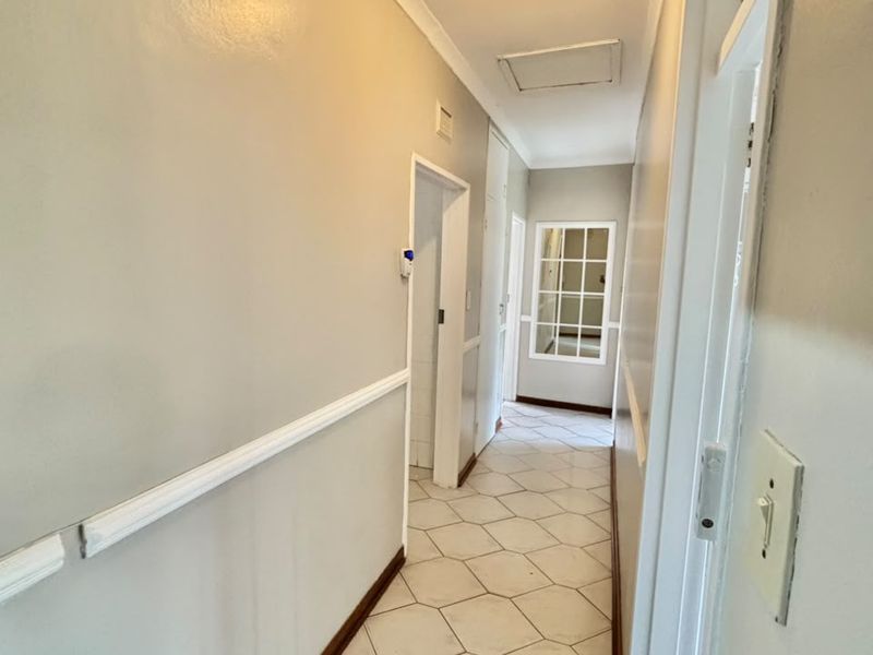 A functional hallway featuring tiled flooring, chair rail molding, and access to multiple rooms, providing a clean and neutral transition space.