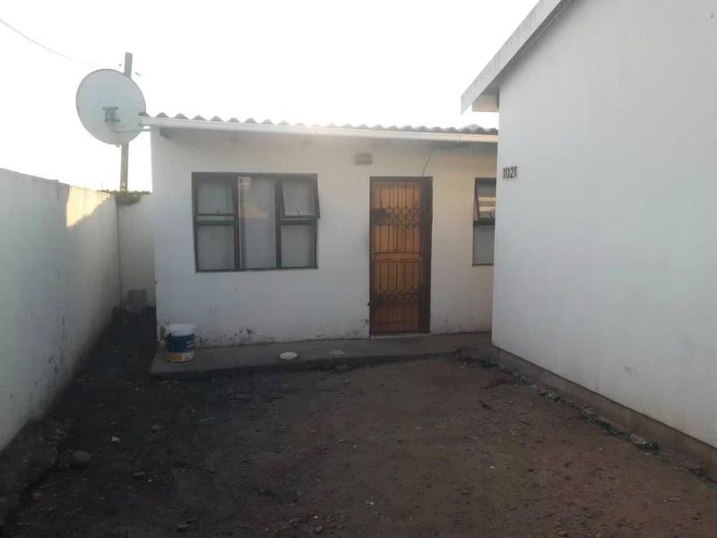 Rear exterior view of the property featuring a security gate, satellite dish, and a concrete apron leading to the entrance.