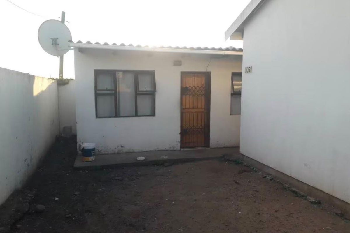 Rear exterior view of the property featuring a security gate, satellite dish, and a concrete apron leading to the entrance.