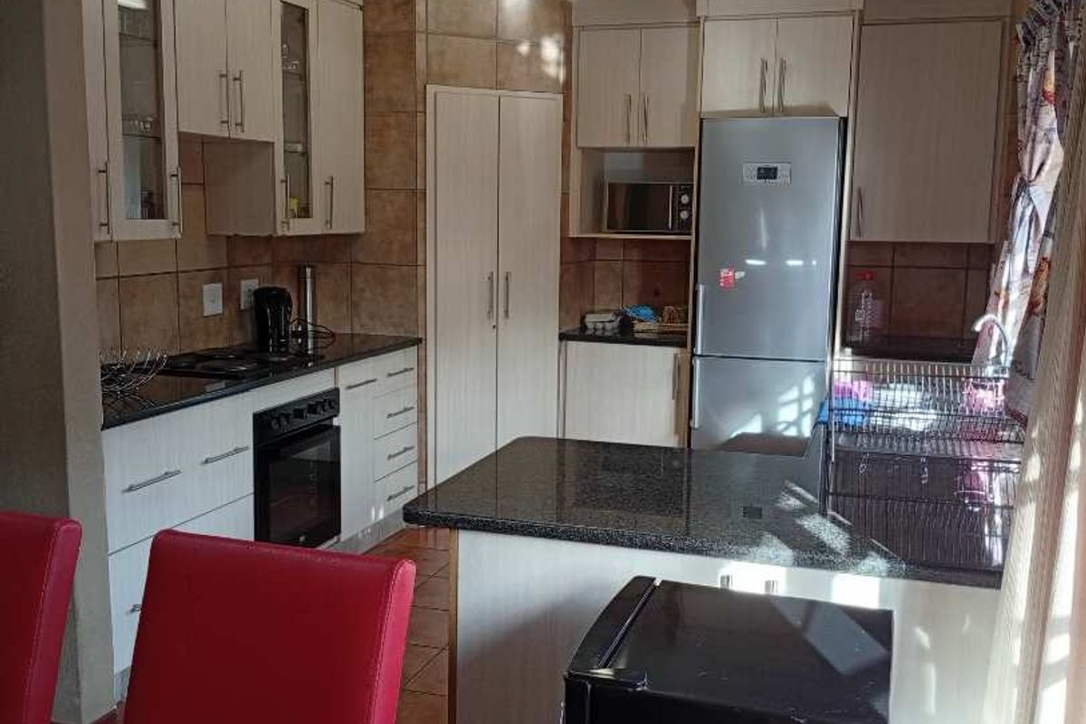 Functional kitchen featuring granite countertops, built-in oven, hob, and ample cabinetry, seamlessly integrated into an open-plan living space.