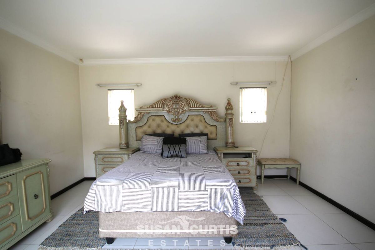 A spacious bedroom featuring tiled flooring, dual windows, and crown molding, providing a neutral canvas for personalization.