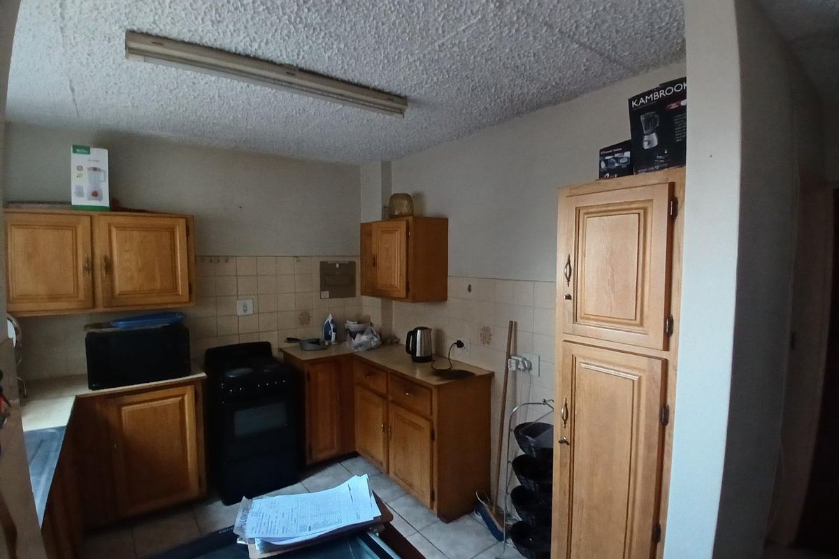 A dated kitchen featuring wooden cabinetry, tiled backsplash, and a freestanding stove, offering potential for modernization and renovation.