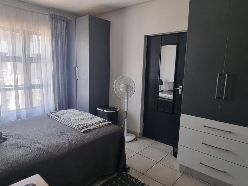 A well-maintained bedroom featuring built-in cupboards with a modern two-tone finish and tiled flooring.