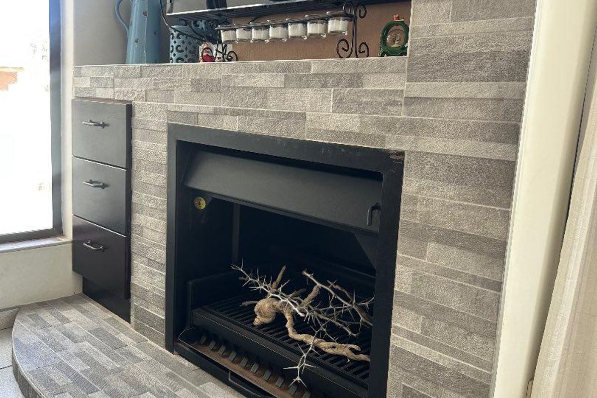 A modern living room feature wall showcasing a built-in fireplace with grey stone cladding, integrated cabinetry, and a raised hearth.
