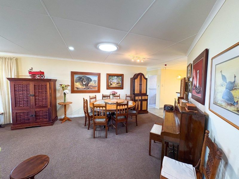 A dining room featuring carpeted flooring and a tiled ceiling with integrated lighting, providing a functional space for family meals.