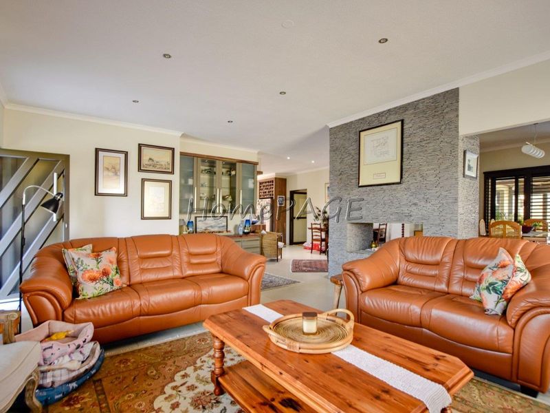 Spacious living room featuring a prominent stone-clad fireplace, recessed downlighting, and integrated display cabinetry, creating a warm and inviting atmosphere.
