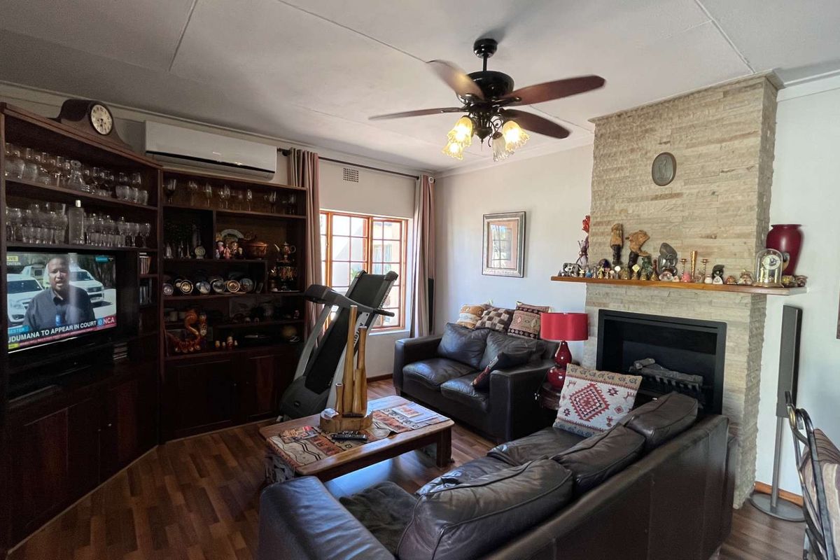 Cozy living room featuring a prominent stone-clad fireplace, built-in wooden cabinetry, ceiling fan, and split-system air conditioning unit.