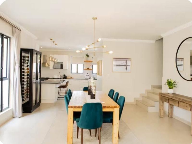 Spacious open-plan living and dining area featuring a modern kitchen with island, sleek cabinetry, and a staircase leading to the upper level.
