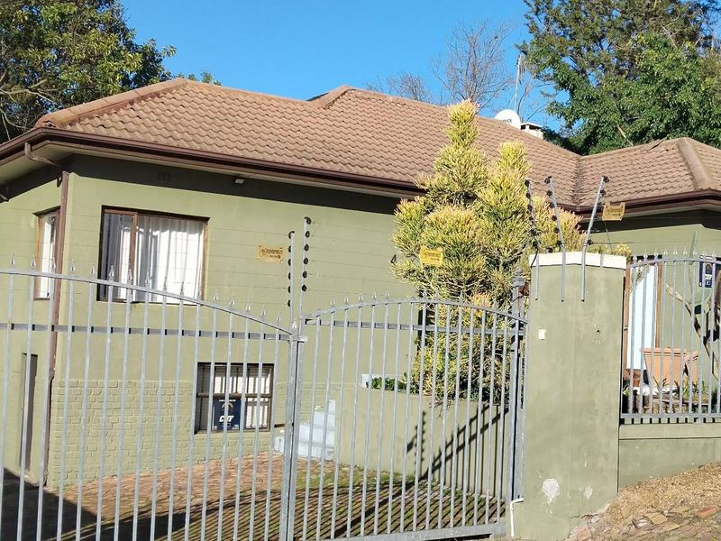 Front exterior view of a single-story residence featuring a tiled roof, perimeter wall with electric fencing, and gated access.