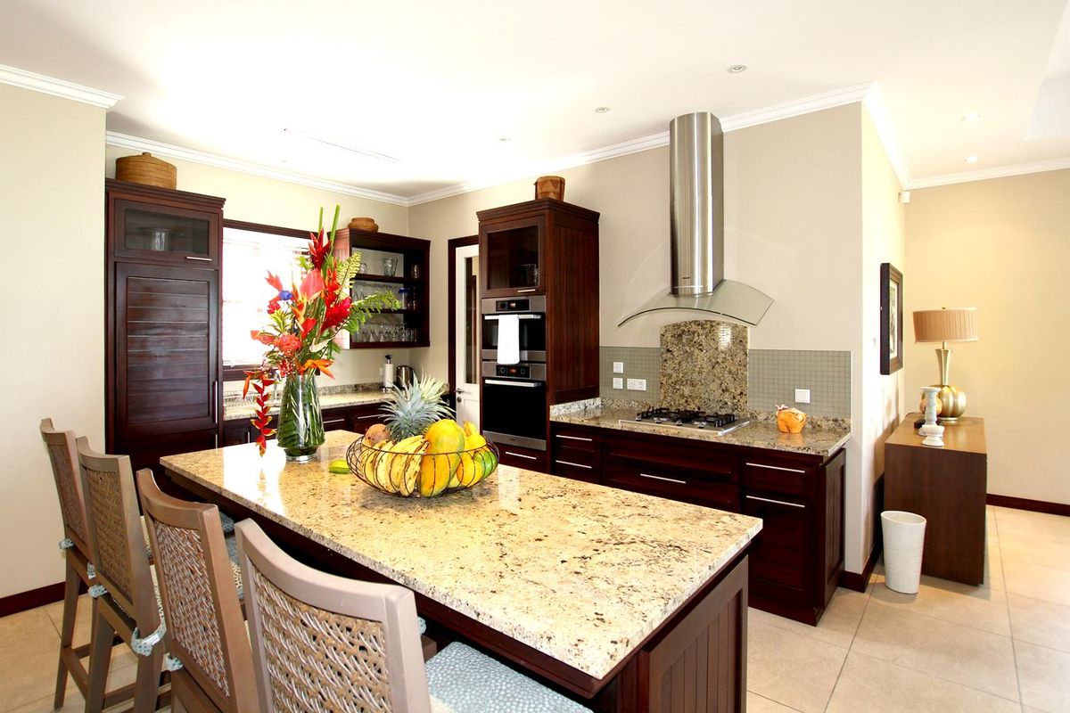 A well-appointed kitchen featuring dark wood cabinetry, granite countertops, a central island with breakfast bar seating, and stainless steel built-in appliances.