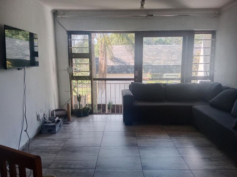 Living room featuring tiled flooring and a large sliding glass door with security bars, providing access to a balcony area.