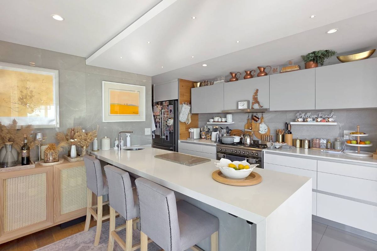 Modern open-plan kitchen featuring a large stone-topped island, sleek cabinetry, integrated appliances, and recessed ceiling lighting.