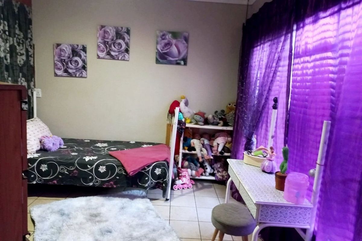 A bedroom featuring tiled flooring and large windows with curtain rails, providing a functional space for a child's room.