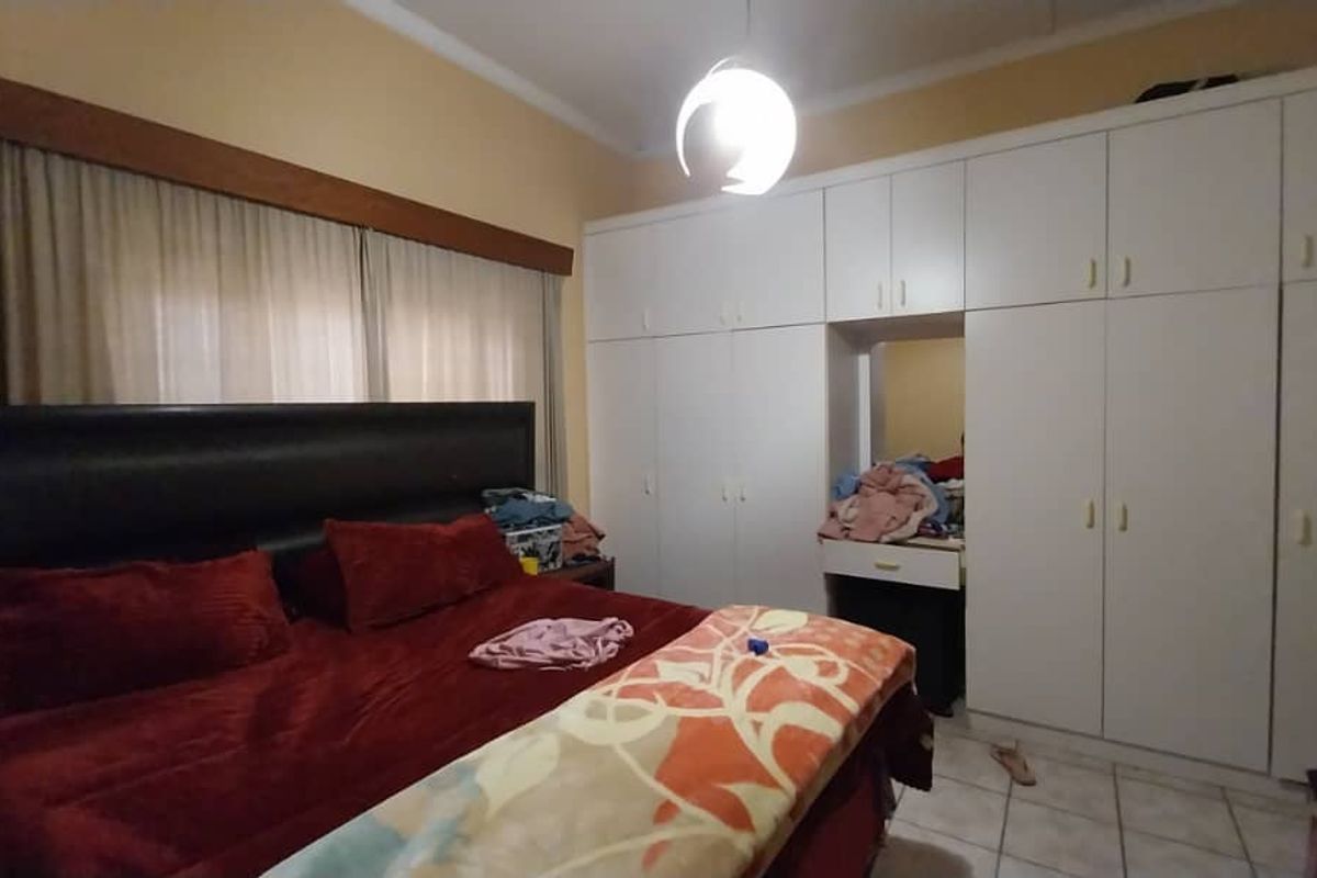 A bedroom featuring extensive built-in white cabinetry with integrated vanity space and tiled flooring.
